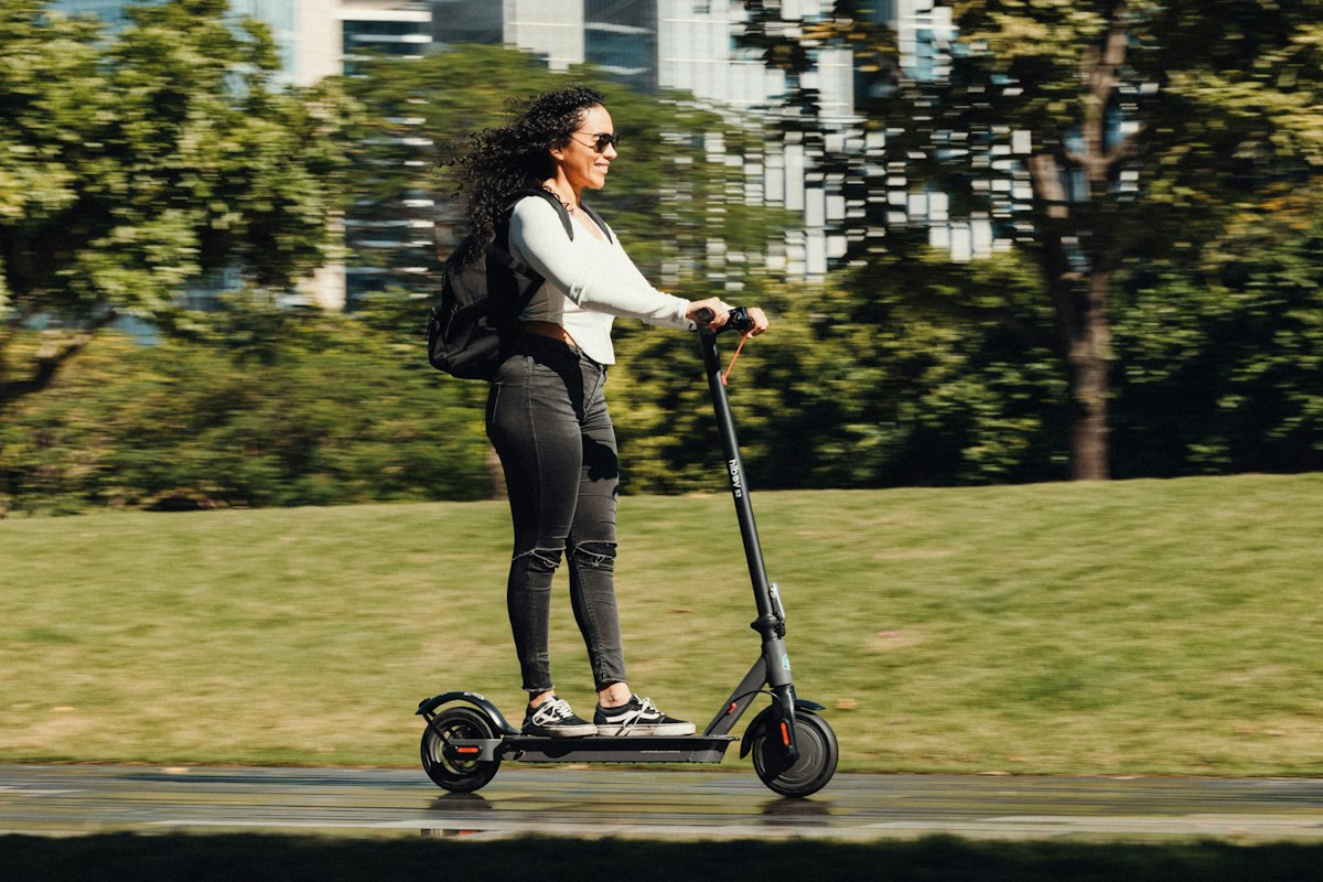 Adult riding an electric scooter along a city cycle path