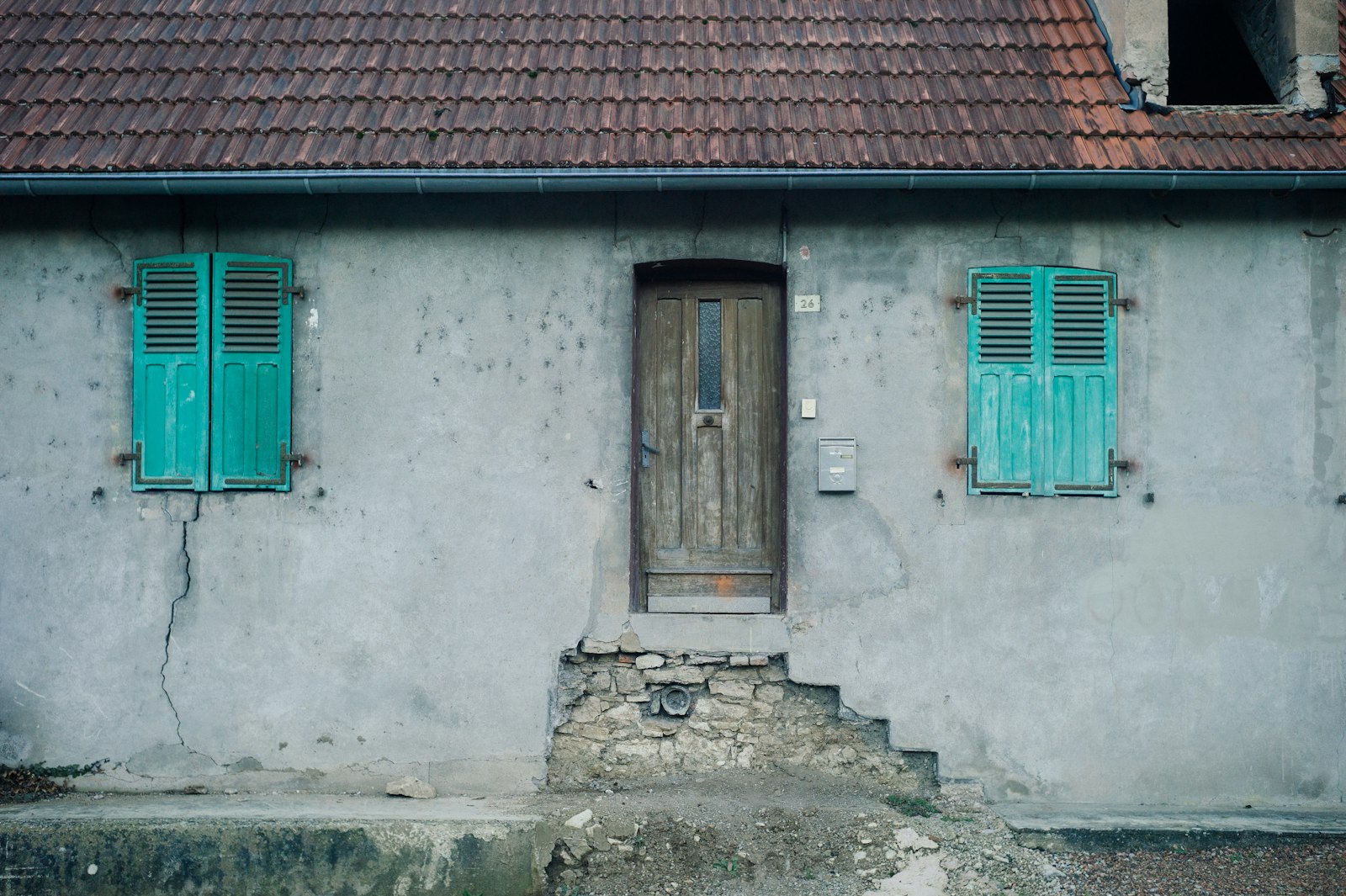 Façade d'une maison de campagne aux volets verts, fermée depuis la saison précédente