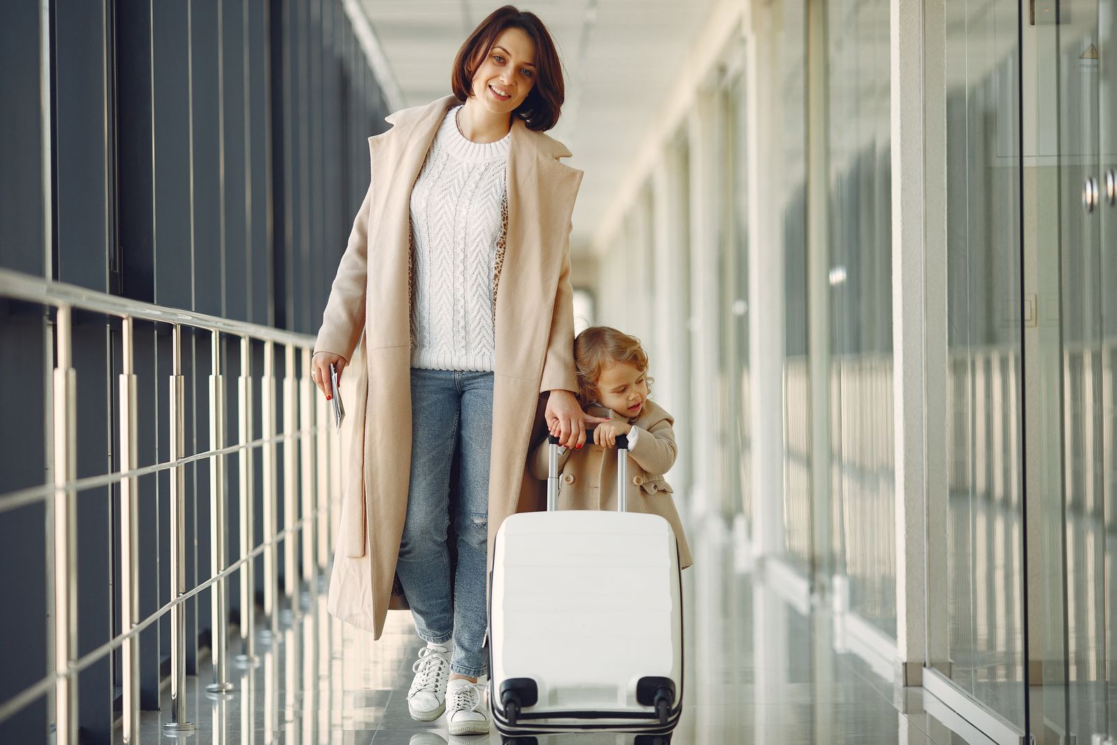 Mère et jeune enfant avec une valise dans un couloir d'aéroport